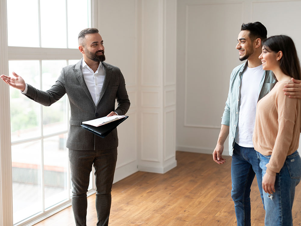 Besichtigung & Beratung – Immobilien kaufen mit Makler Immobilienmakler berät ein Paar bei der Wohnungsbesichtigung in einem hellen Raum